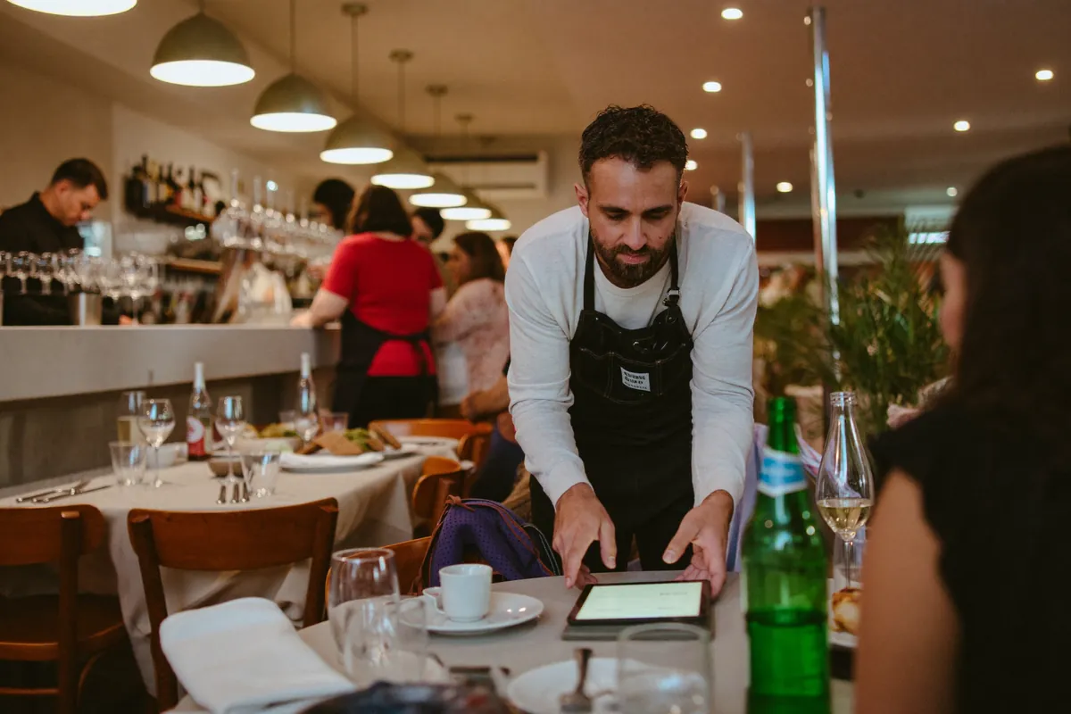 Mozo de un restobar toma un pedido desde una tablet