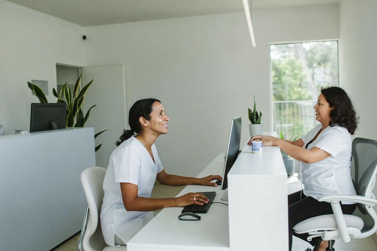 Recepcionista de una clínica atiende a una paciente